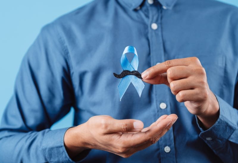 Homem segurando uma fitinha azul, em alusão ao Novembro Azul, mês de conscientização contra o câncer de próstata.