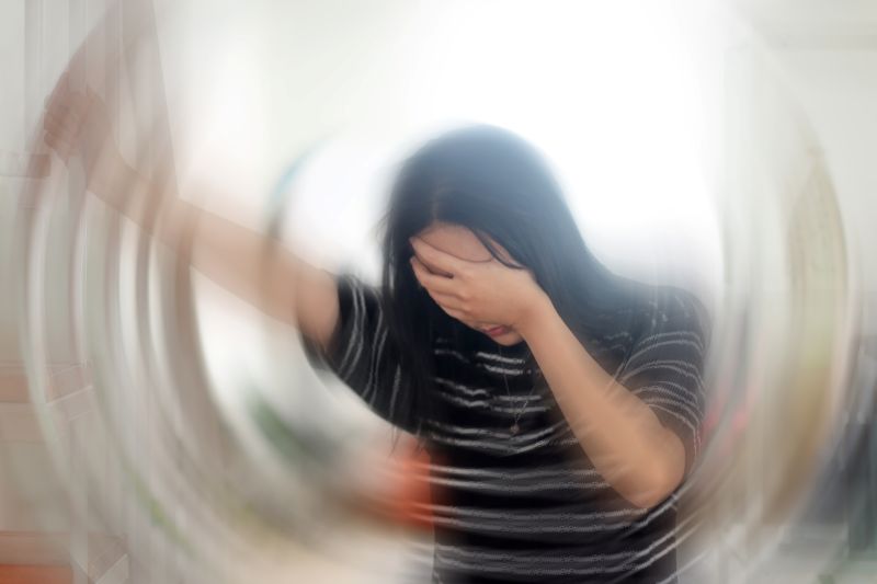 Quais os sintomas da labirintite: Mulher com a mão no rosto, em provável episódio de tontura por labirintite.