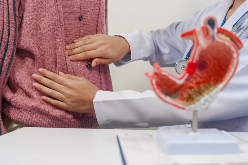Médico examina paciente na região da barriga, para verificar uma possível infecção intestinal.